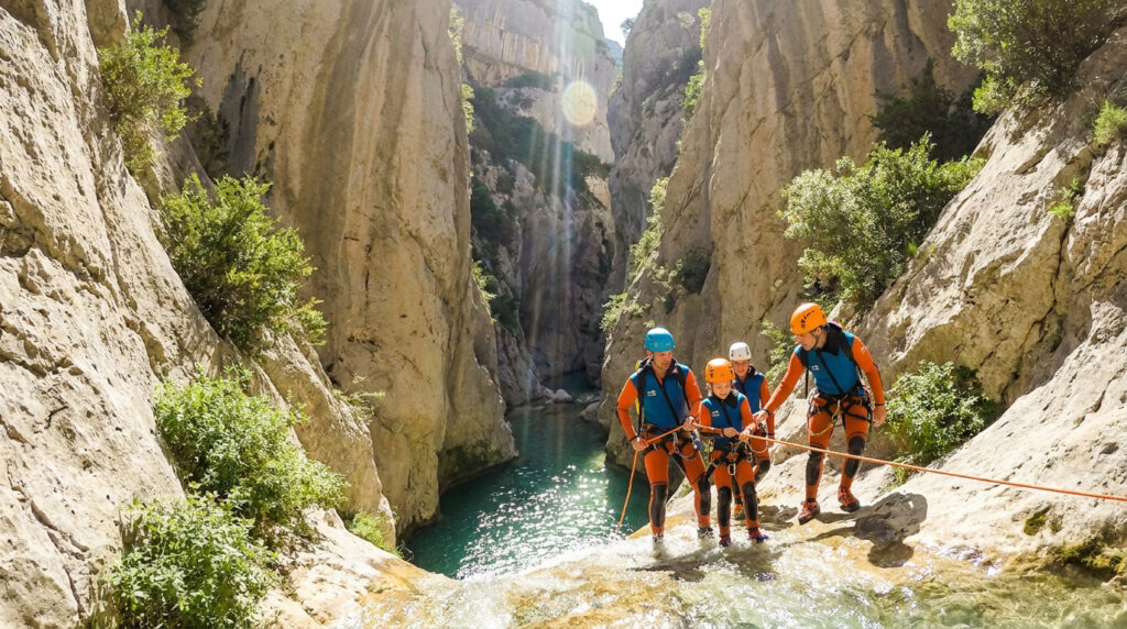 Groupe en combinaison de canyoning préparant une descente en rappel dans les Gorges du Verdon sous le soleil.