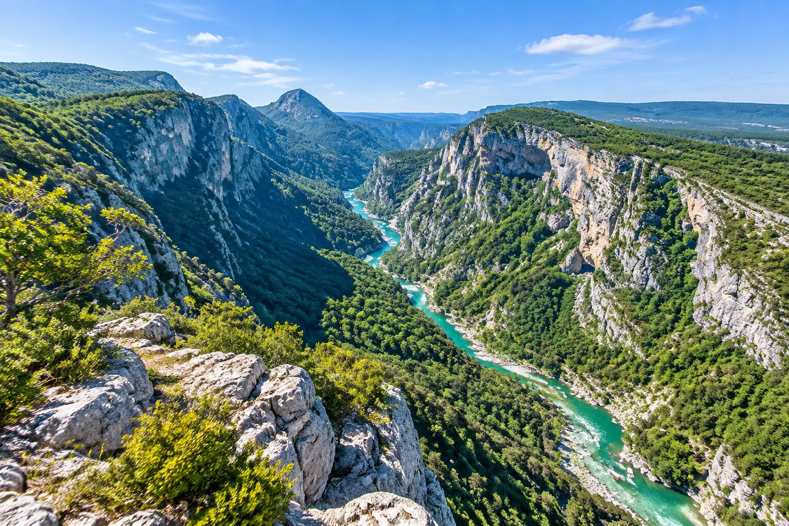 Une rivière turquoise serpente au fond d’un profond canyon bordé de falaises rocheuses et de forêts, sous un ciel bleu dégagé.