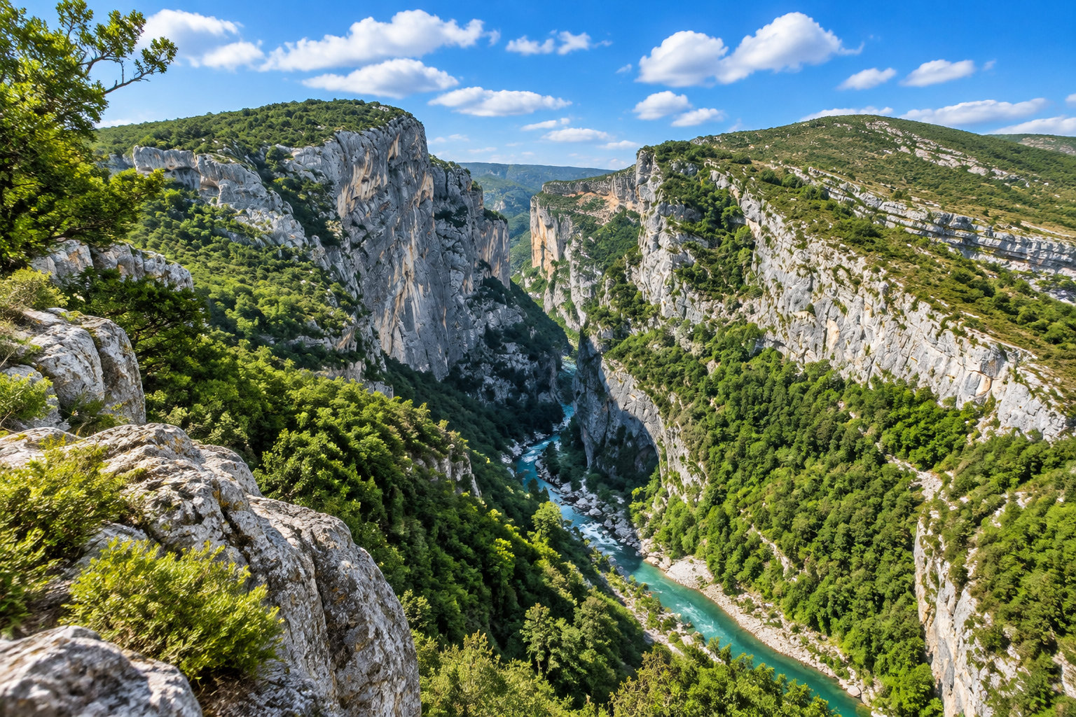 Un canyon bordé de falaises calcaires et de végétation verdoyante, traversé par une rivière turquoise sous un ciel ensoleillé.
